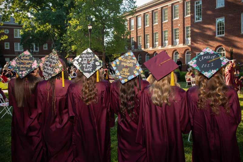 Six graduates showing their caps