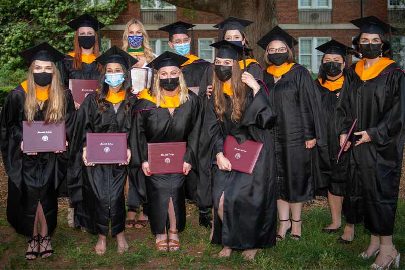 New graduates posing with diplomas and hoods