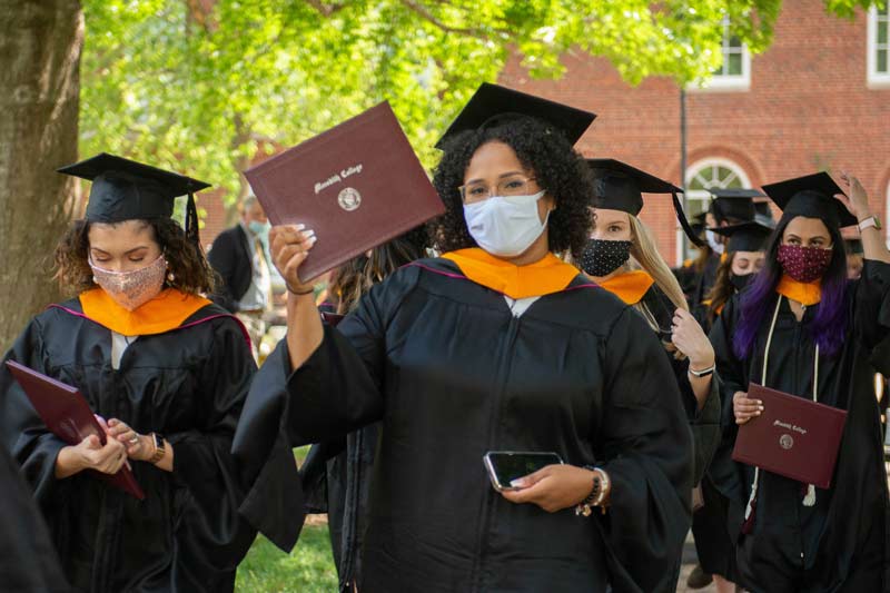 New graduates posing with diplomas and hoods