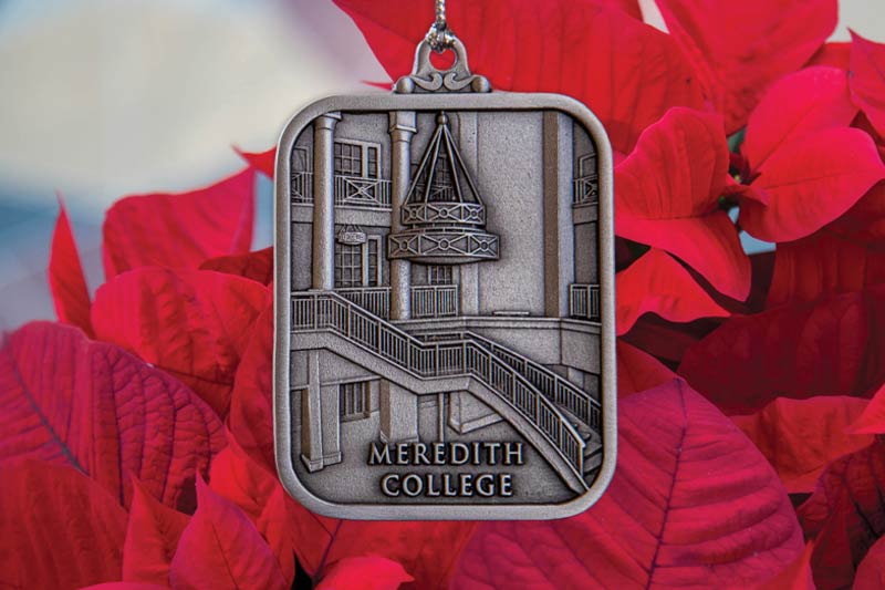 A metal ornament of Meredith's Johnson Hall with a red background.