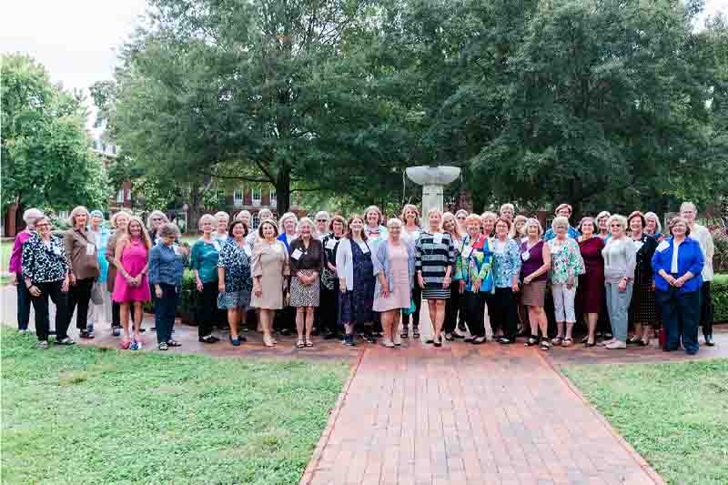 A group of alumnae smiling for a photo in front of the fountain.