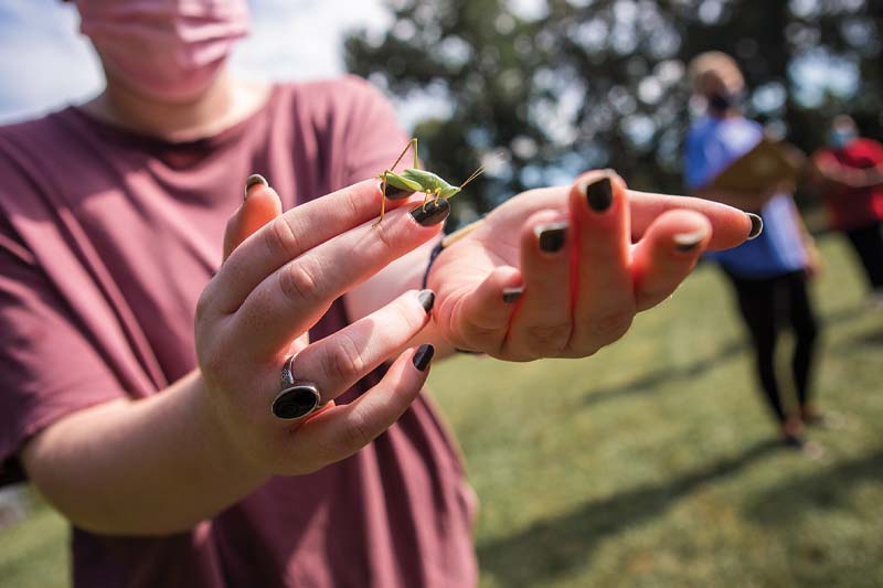 A student wearing her ring shows off a grasshopper.