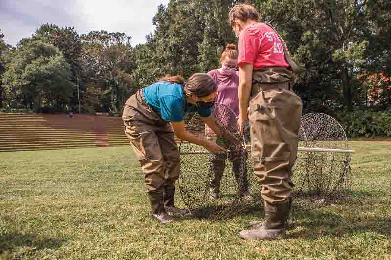 Students in weighters adjust a catch net