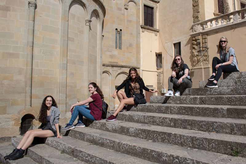 Students in Italy smiling on steps.