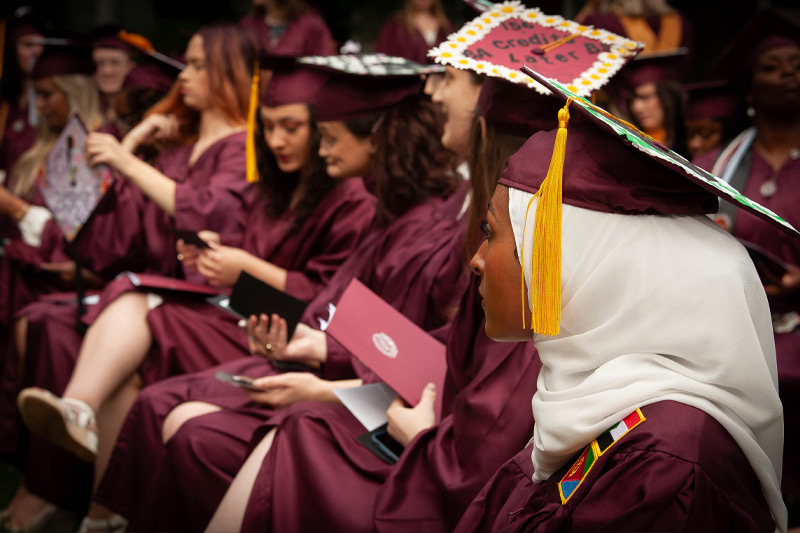Students sitting at with their caps and gowns.