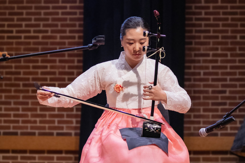A student performs music on an eastern musical instrument.