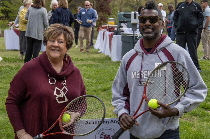 Dr. Allen and a Meredith Athletics member with tennis rackets.