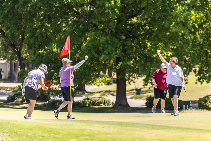 People cheering after putting a ball in the hole during the golf tournament.