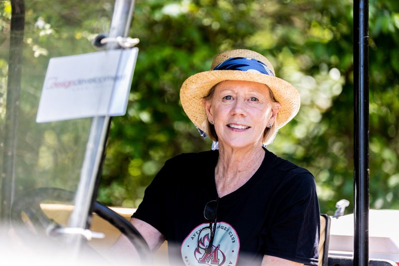 A woman smiles from a golf cart.