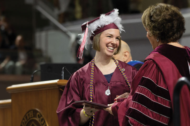 A wings student smiles as she receives her diploma from Dr. Allen.