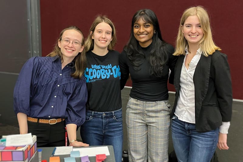 Four students smile at a table on Engineering Day.