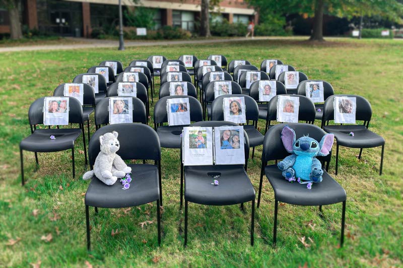 Chairs lined with stories of people and children who have been affected by domestic violence.