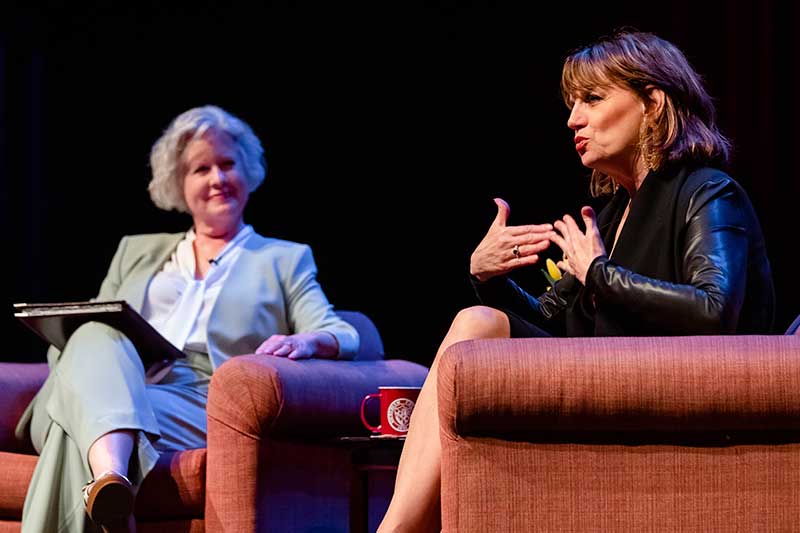 Beth Leavel and a host sit in chairs while she talks.