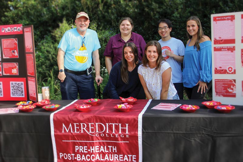 Students and Faculty and Staff at a table for the Pre-Health post-baccalaureate table on plasma donations.